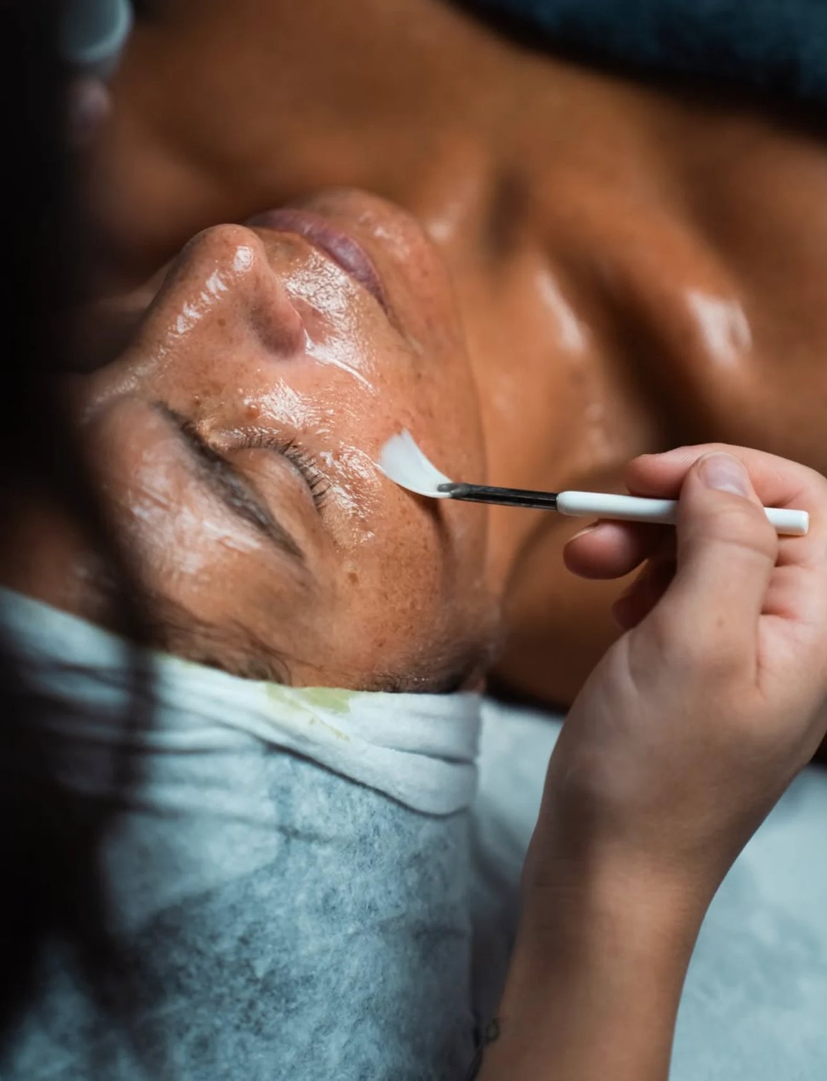 Makeup artist applying eyeshadow to a clients eyelid with a brush during a beauty procedure